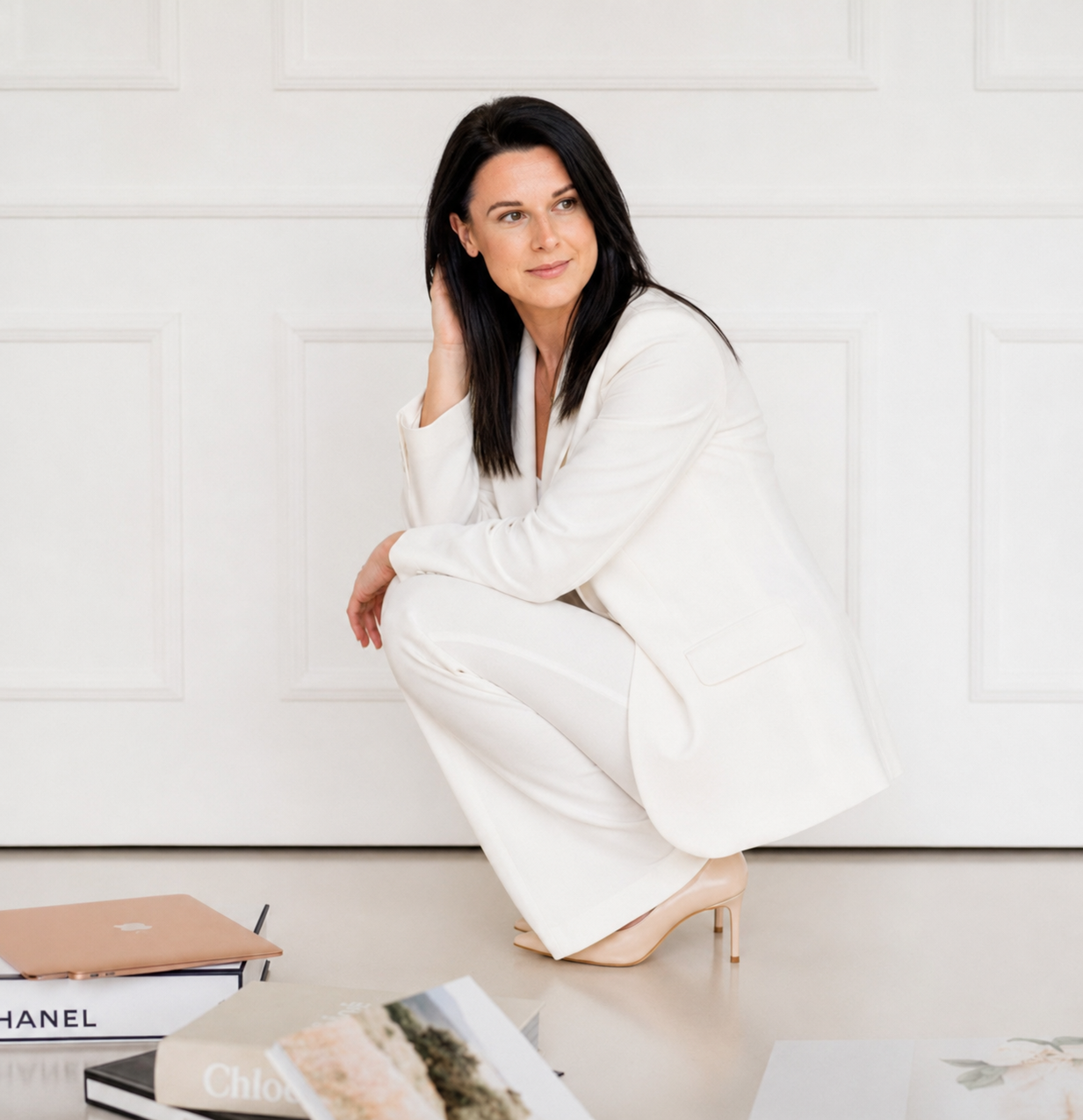 Katie Lyth in a white suit with Chanel and Chloé books